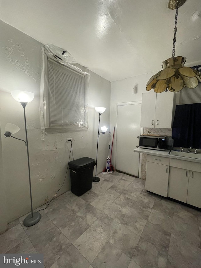 kitchen featuring decorative backsplash, white cabinetry, and sink