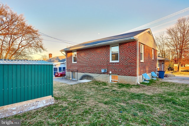 property exterior at dusk with a lawn and a storage shed