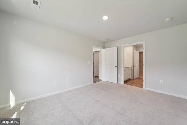 unfurnished bedroom with light carpet and connected bathroom