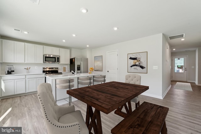 dining space with sink and light hardwood / wood-style flooring