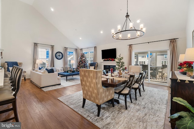 dining area with high vaulted ceiling, wood-type flooring, and an inviting chandelier