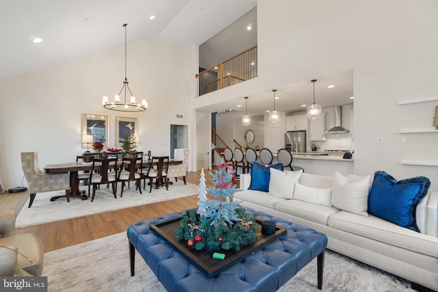 living room with high vaulted ceiling, light hardwood / wood-style floors, and an inviting chandelier