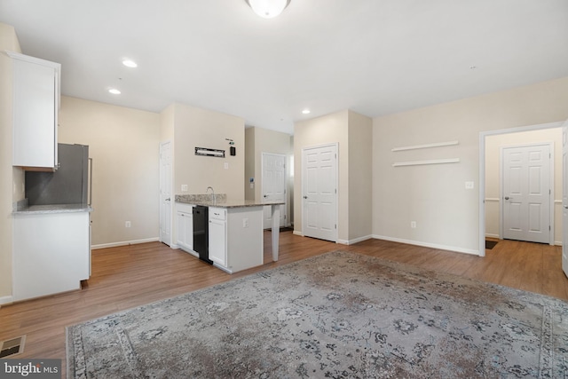 kitchen with white cabinets, light wood-type flooring, and stainless steel refrigerator