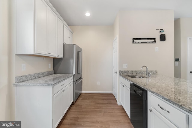 kitchen with sink, black dishwasher, light stone counters, high quality fridge, and white cabinets