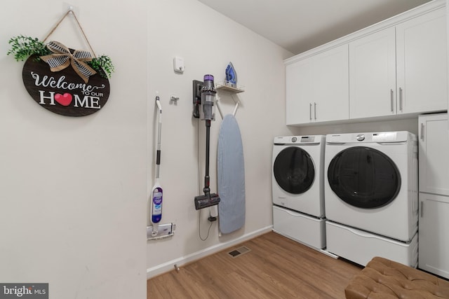 washroom with washer and clothes dryer, cabinets, and light hardwood / wood-style flooring