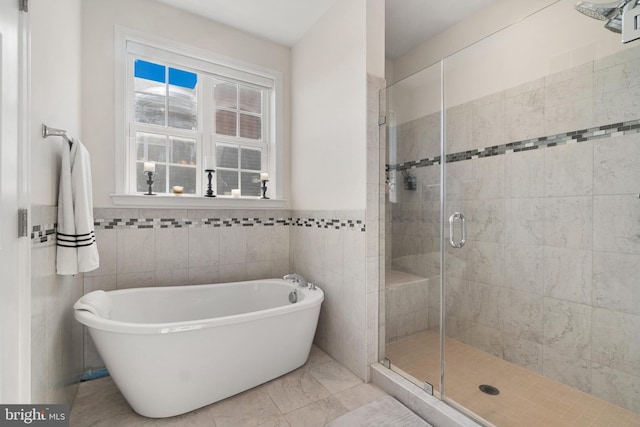 bathroom with tile patterned flooring, tile walls, and plus walk in shower