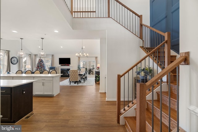 kitchen with white cabinetry, a towering ceiling, pendant lighting, light hardwood / wood-style floors, and a kitchen island