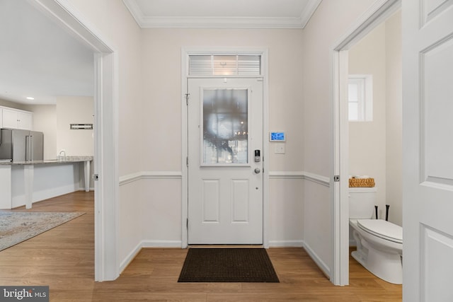 foyer featuring ornamental molding and light hardwood / wood-style flooring