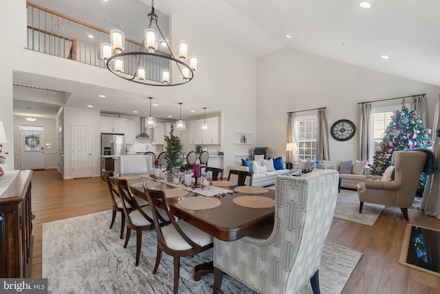 dining room featuring high vaulted ceiling, light hardwood / wood-style floors, and a notable chandelier