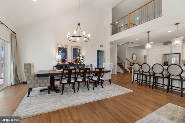 dining room featuring an inviting chandelier, a towering ceiling, and hardwood / wood-style flooring