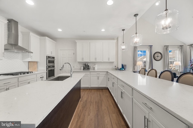 kitchen with a breakfast bar, stainless steel appliances, tasteful backsplash, and wall chimney exhaust hood