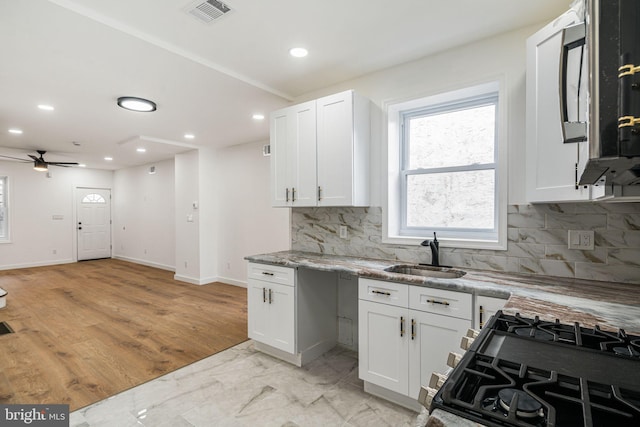 kitchen featuring white cabinetry, sink, ceiling fan, black range with gas cooktop, and light wood-type flooring