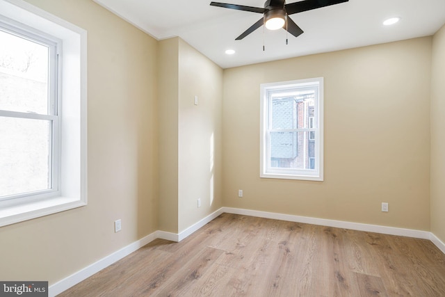 spare room with light wood-type flooring, a wealth of natural light, and ceiling fan