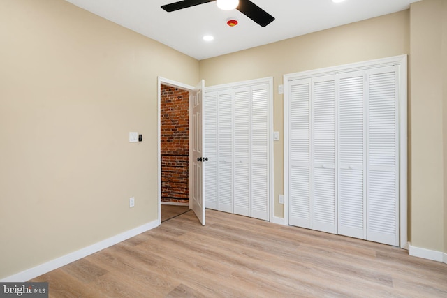 unfurnished bedroom featuring multiple closets, ceiling fan, and light hardwood / wood-style floors