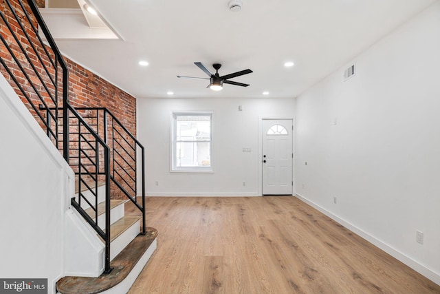 foyer featuring ceiling fan, light wood-type flooring, and brick wall