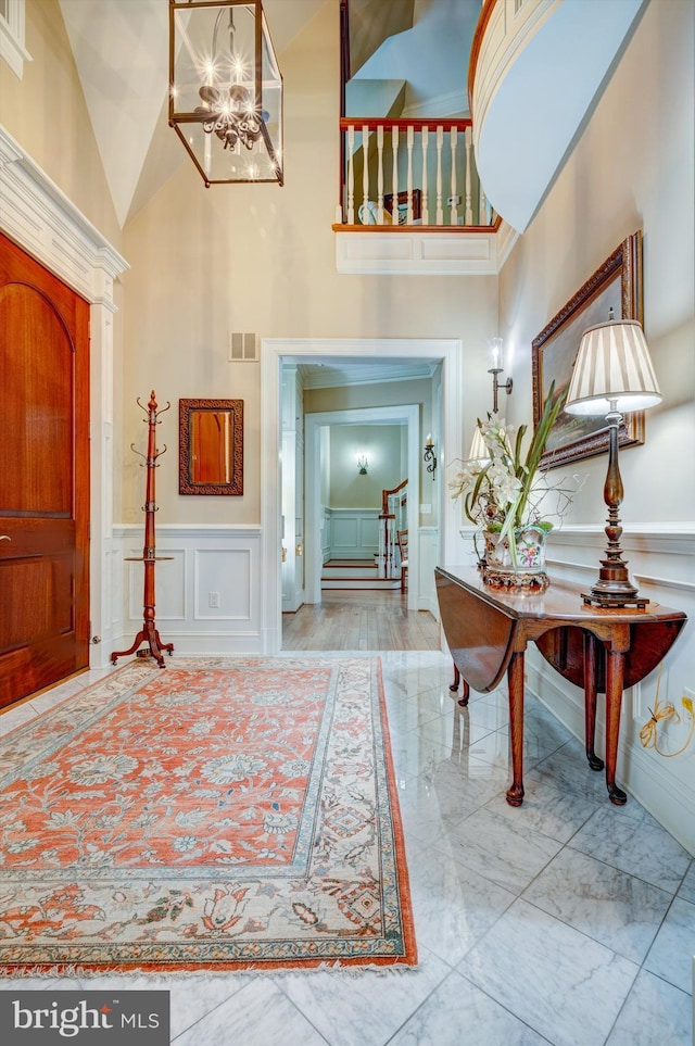 entryway featuring light hardwood / wood-style flooring, high vaulted ceiling, and a notable chandelier