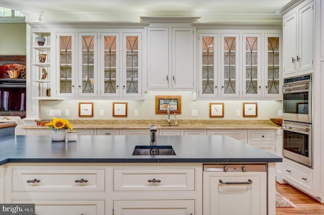 kitchen featuring white cabinetry, light wood-type flooring, stainless steel double oven, and sink