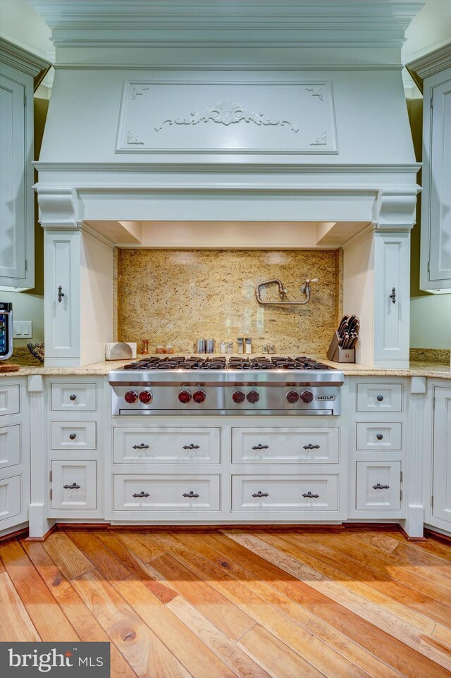 kitchen with tasteful backsplash, light stone countertops, light hardwood / wood-style floors, and stainless steel gas cooktop