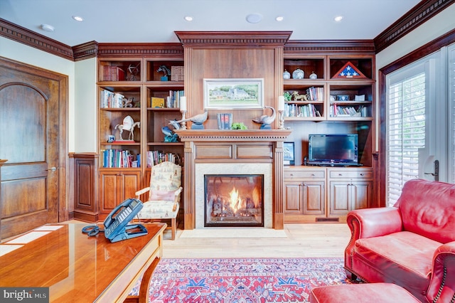 living room featuring light wood-type flooring, ornamental molding, and a high end fireplace