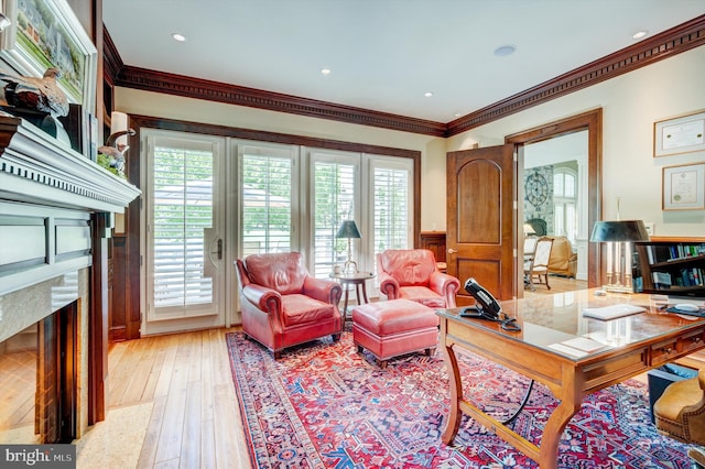 living room with plenty of natural light, light wood-type flooring, crown molding, and a high end fireplace