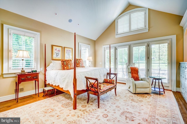 bedroom featuring access to exterior, hardwood / wood-style flooring, and multiple windows