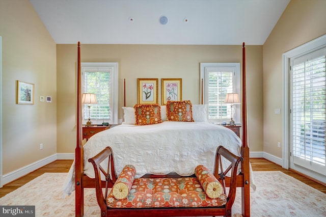 bedroom featuring vaulted ceiling, light hardwood / wood-style flooring, and multiple windows