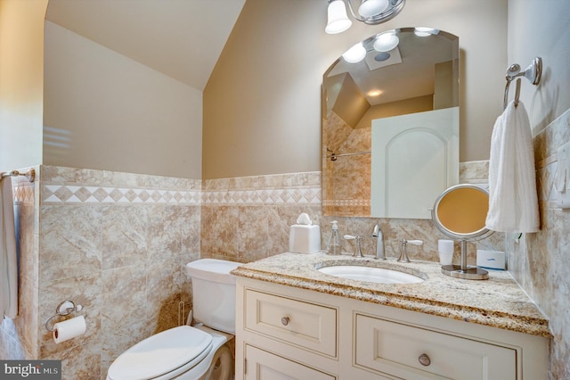 bathroom featuring vanity, toilet, lofted ceiling, and tile walls