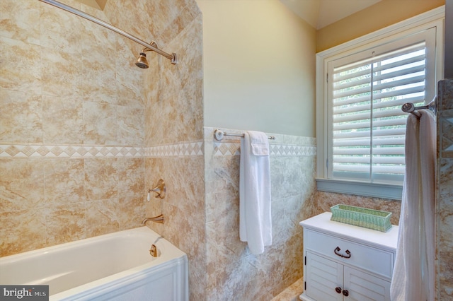 bathroom with tiled shower / bath combo and tile walls