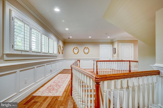 corridor with light wood-type flooring and crown molding