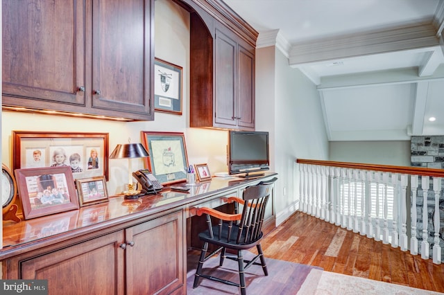 office area featuring beamed ceiling, built in desk, light hardwood / wood-style floors, and ornamental molding