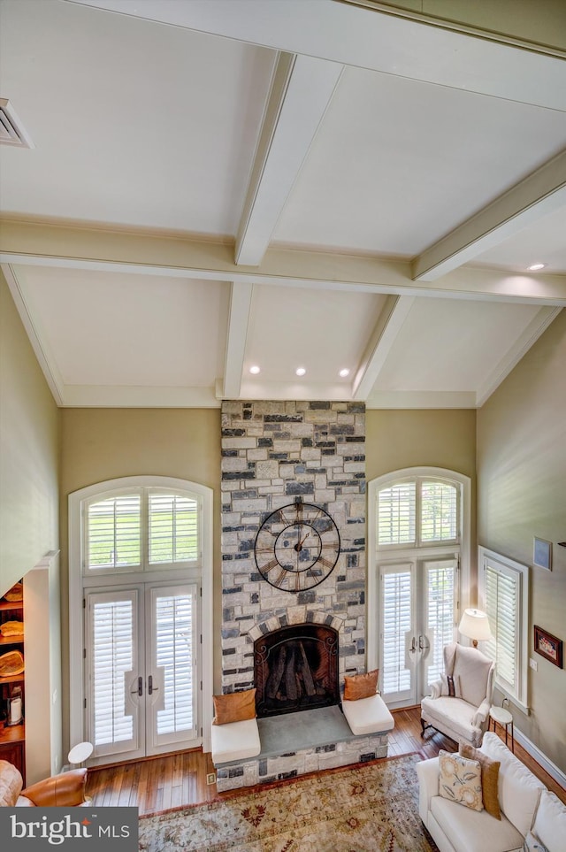 living room with hardwood / wood-style floors, beam ceiling, a fireplace, and french doors