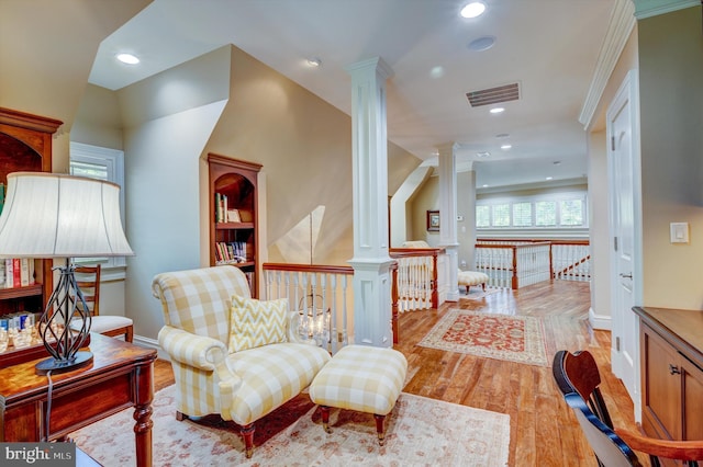 sitting room with light wood-type flooring, decorative columns, and crown molding