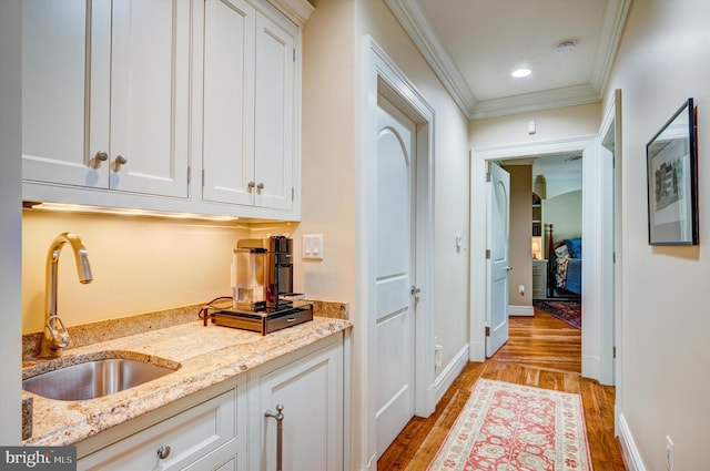 interior space with light hardwood / wood-style floors, ornamental molding, and sink