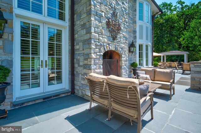 view of patio with an outdoor living space with a fireplace and french doors