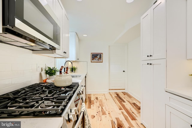 kitchen featuring white cabinets, light wood-type flooring, and stainless steel appliances