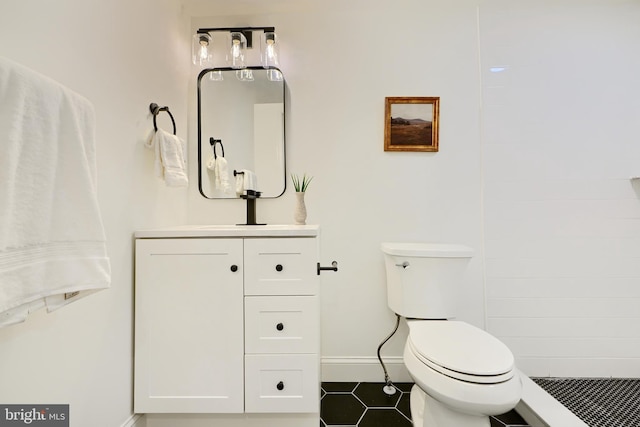 bathroom featuring tile patterned flooring, vanity, toilet, and walk in shower