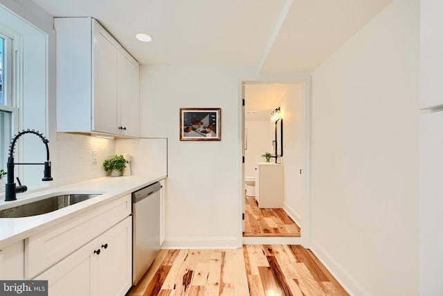 kitchen with sink, dishwasher, plenty of natural light, white cabinets, and light wood-type flooring