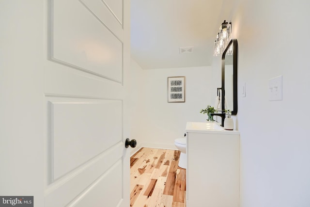 bathroom with hardwood / wood-style floors, vanity, and toilet