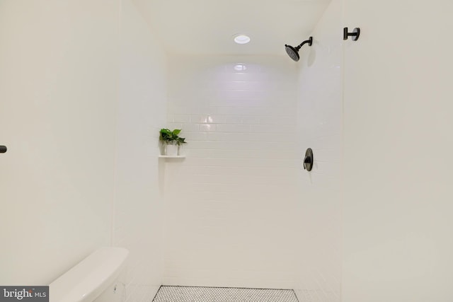 bathroom featuring a tile shower and toilet