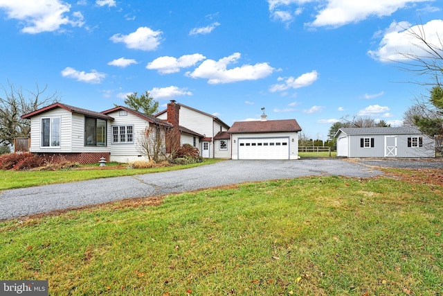 view of front facade with an outbuilding, a garage, and a front lawn