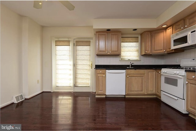 kitchen with a wealth of natural light, dark hardwood / wood-style floors, and white appliances