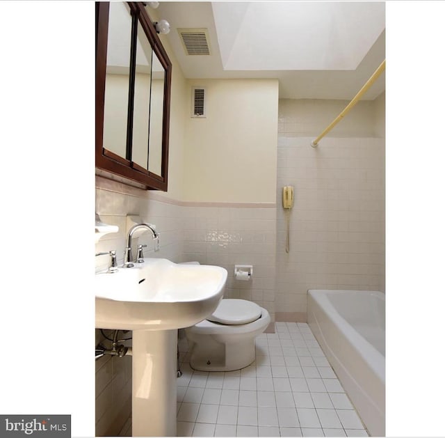 bathroom with tile patterned floors, toilet, and tile walls