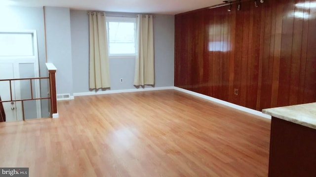 unfurnished room featuring wooden walls and light hardwood / wood-style flooring