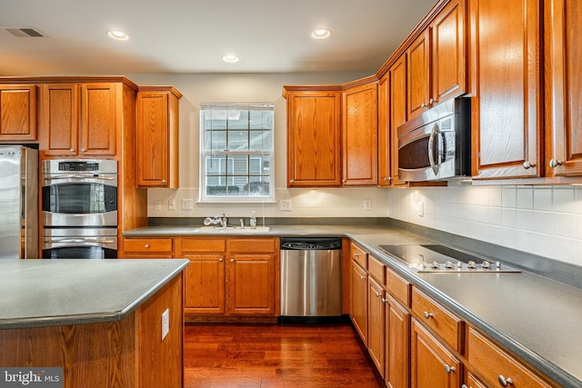 kitchen featuring stainless steel appliances, sink, backsplash, and dark hardwood / wood-style flooring