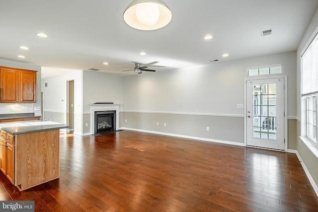 unfurnished living room featuring ceiling fan and dark hardwood / wood-style flooring