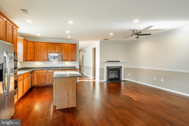 kitchen with dark wood-type flooring, a kitchen island, ceiling fan, stainless steel appliances, and decorative backsplash