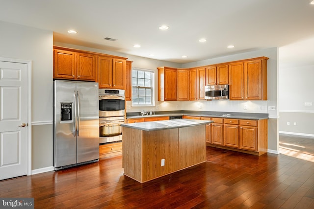 kitchen with appliances with stainless steel finishes, a center island, dark wood-type flooring, and sink