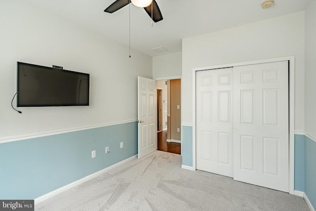 unfurnished bedroom featuring light colored carpet, ceiling fan, and a closet