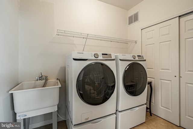 washroom featuring separate washer and dryer, sink, and light tile patterned floors