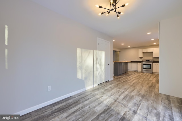 unfurnished living room with a chandelier and light hardwood / wood-style floors